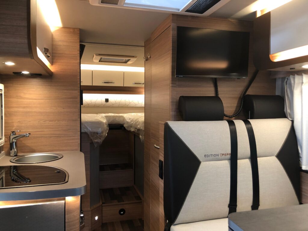 Innenansicht Wohnmobil mit Blickauf Sitzecke, Küche und Bett