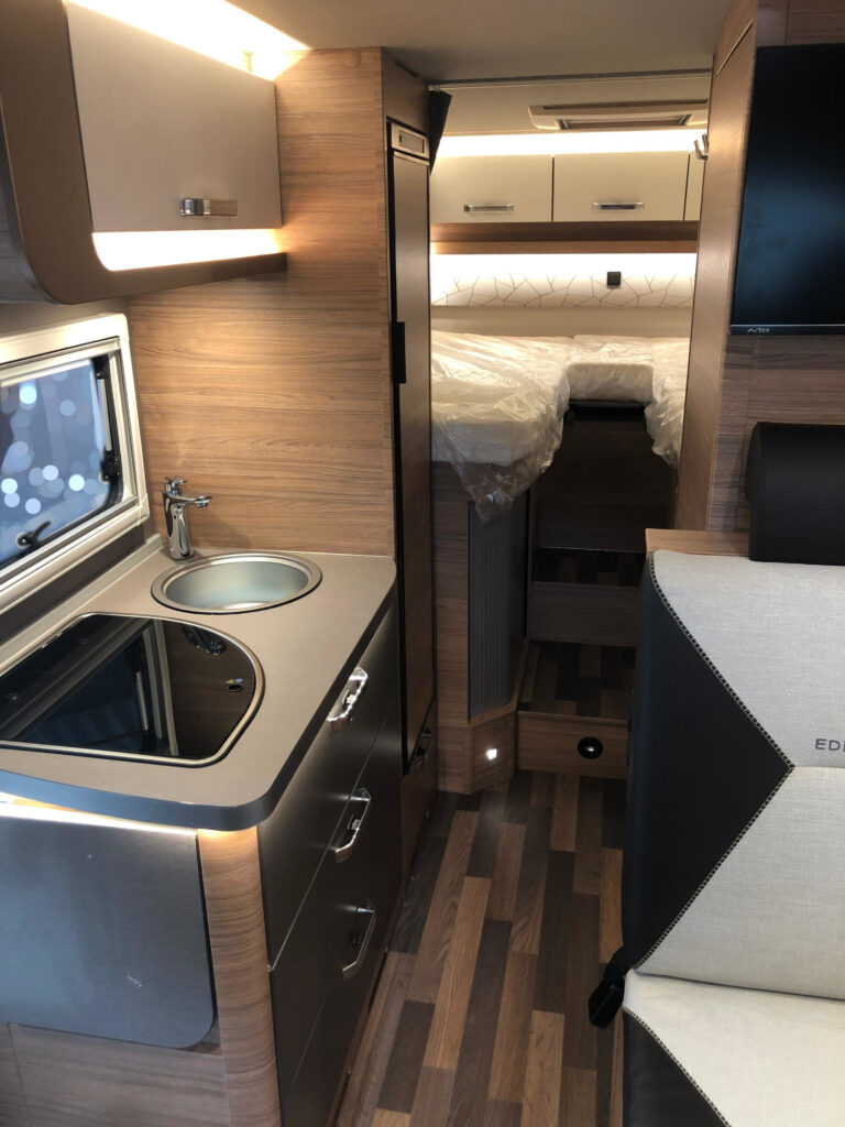 Innenansicht Wohnmobil mit Blickauf Sitzecke, Küche und Bett